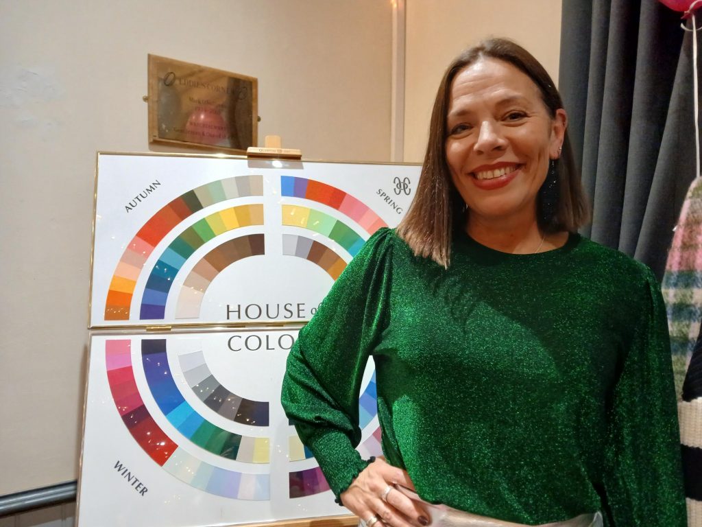 Kate Moss-Jones wearing an emerald green top, stood next to a color wheel.