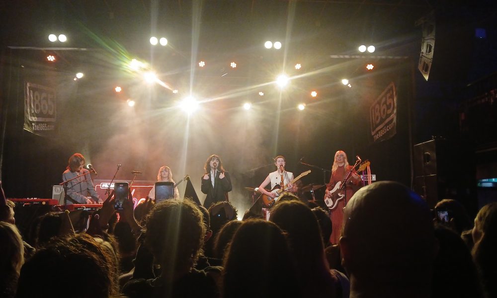 Photo taken by Meadbh Corbett. Aurora Nishevci, Emily Roberts, Abigail Morris, Lizzie Mayland and Georgia Davies on stage performing their song 'Agnus Dei'