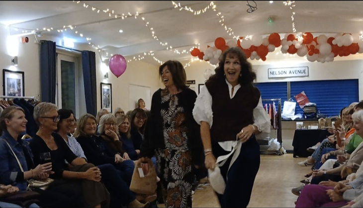 Two models playfully strutting down the runway and interacting with the crowd